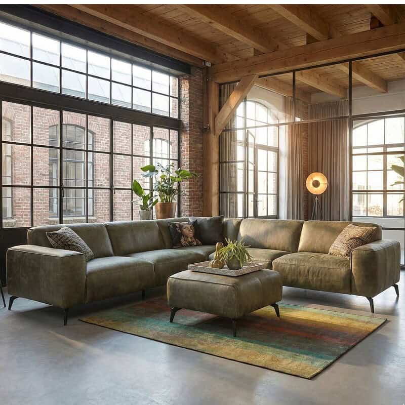 1. Industriële leren hoekbank in een loft met grote ramen, warme houtdetails en vintage sfeer, perfect voor modern wonen met een rauwe, stijlvolle uitstraling.