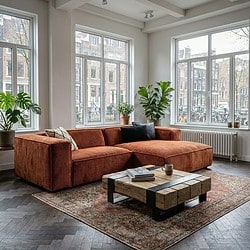 Rustkleurige bank in Scandinavisch interieur met grote ramen, houten vloer en planten, modern en gezellig wonen, maatwerk meubels, woonkamer inrichting door Mokana Meubelen.