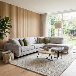 Elegante moderne woonkamer met strakke, lichtgrijze L-vormige bank en natuurstenen salontafels, grote raampartijen en natuurlijke houten wand, perfecte combinatie van comfort en stijl.