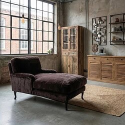 Robuuste bank met donkerbruine bekleding in een industrieel interieur, gecombineerd met houten kasten en decoratieve elementen voor een sfeervol woonkamerontwerp.