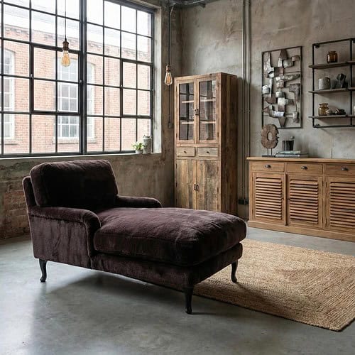 ace1e87a-1696-4af1-afb6-5befb3b77ec0 Robuuste bank met donkerbruine bekleding in een industrieel interieur, gecombineerd met houten kasten en decoratieve elementen voor een sfeervol woonkamerontwerp.