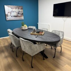Modern eettafel met donker houten blad en metalen poten, omringd door stijlvolle comfortabele stoelen in een eigentijds interieur met een opvallende blauwe accentmuur.