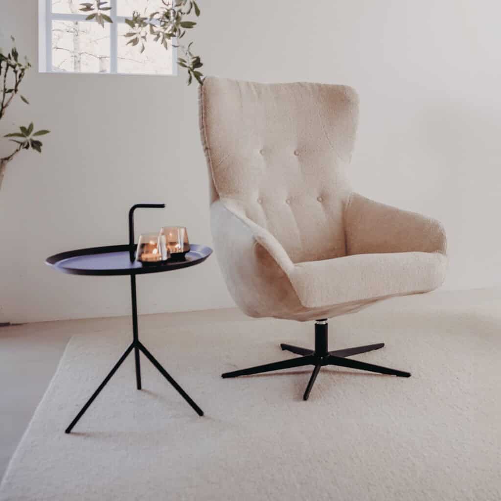 Luxe beige relaxfauteuil met moderne zwarte onderstel en bijpassende bijzettafel, perfect voor een gezellige zithoek met stijlvolle meubels.