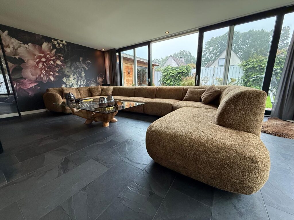 Lange moderne bank met zachte kussens in een stijlvolle woonkamer met grote raampartijen en uitzicht op de tuin, accentueert luxe en comfort.