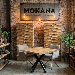 Elegante houten eettafel met industrieel design, perfect voor modern vintage interieur, gecombineerd met comfortabele stoelen, in een stijlvolle winkel met brick wall en unieke wanddecoratie.