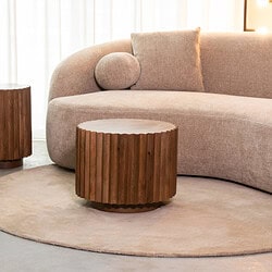 Elegant hoekbank met modern stof in zacht roze, gecombineerd met houten bijzettafels voor een stijlvolle woonkamer. Op maat gemaakte meubelen voor comfort en design.