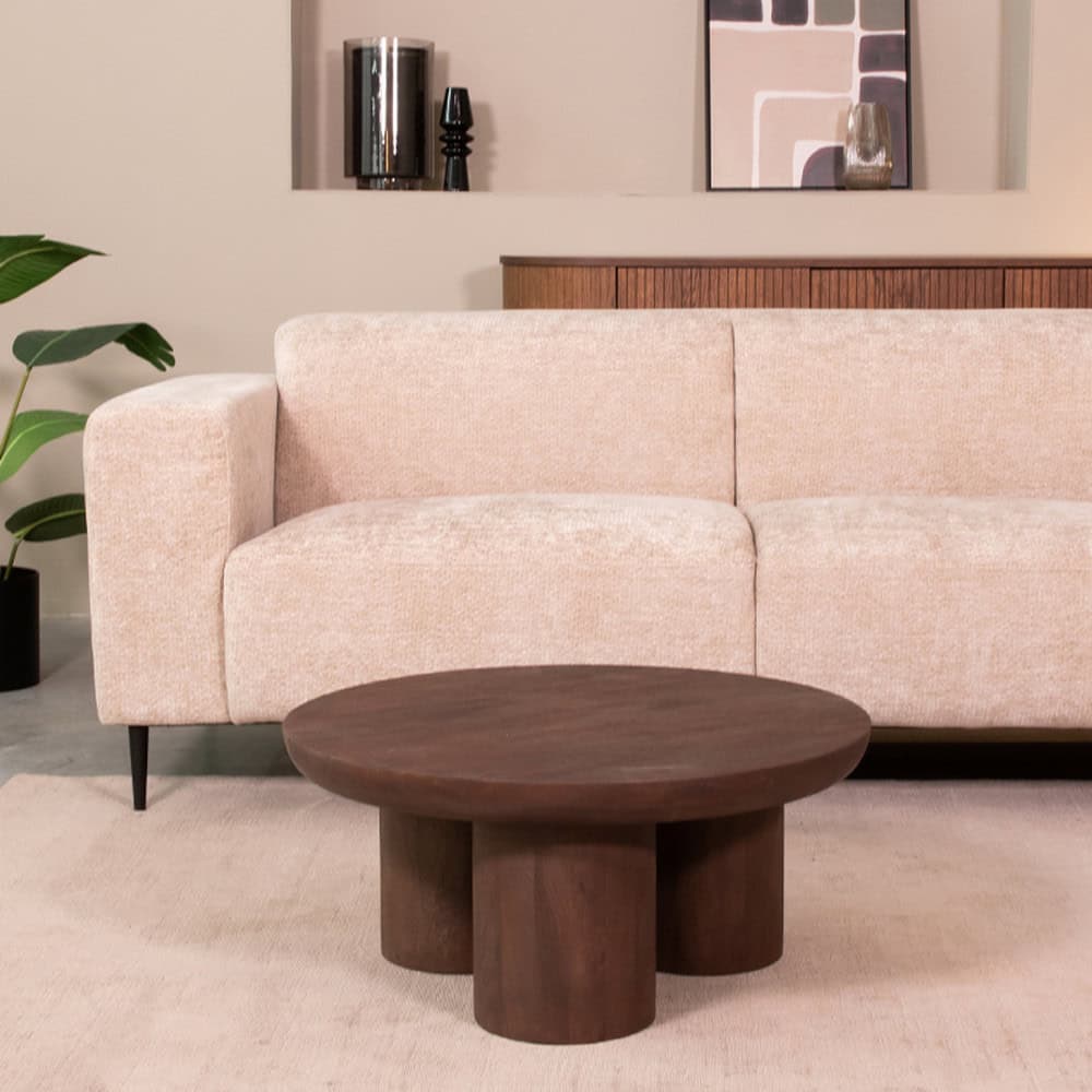 Elegante landelijke woonkamer met een zachte, lichtroze stoffen bank en een robuuste houten salontafel, decorated met moderne accessoires en bloemen voor een warm en stijlvol interieur.