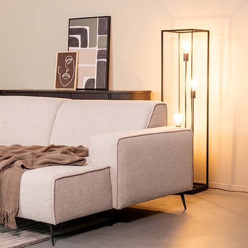 Modern beige stofferen bank met zwarte metalen poten in een eigentijdse woonkamer.