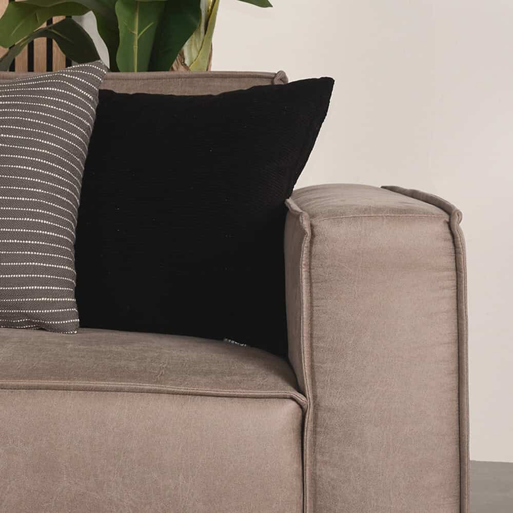 Elegante beige bank met stoffen kussens, inclusief zwarte en gestreepte sierkussens, perfect voor stijlvolle en comfortabele zithoeken.