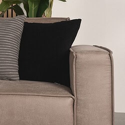 Elegante beige bank met stoffen kussens, inclusief zwarte en gestreepte sierkussens, perfect voor stijlvolle en comfortabele zithoeken.