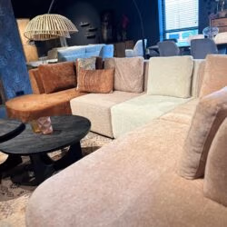 Elegant stoffen zithoek met modulaire bank in diverse pastel- en aardetinten, perfect voor gezellige woonkamers.