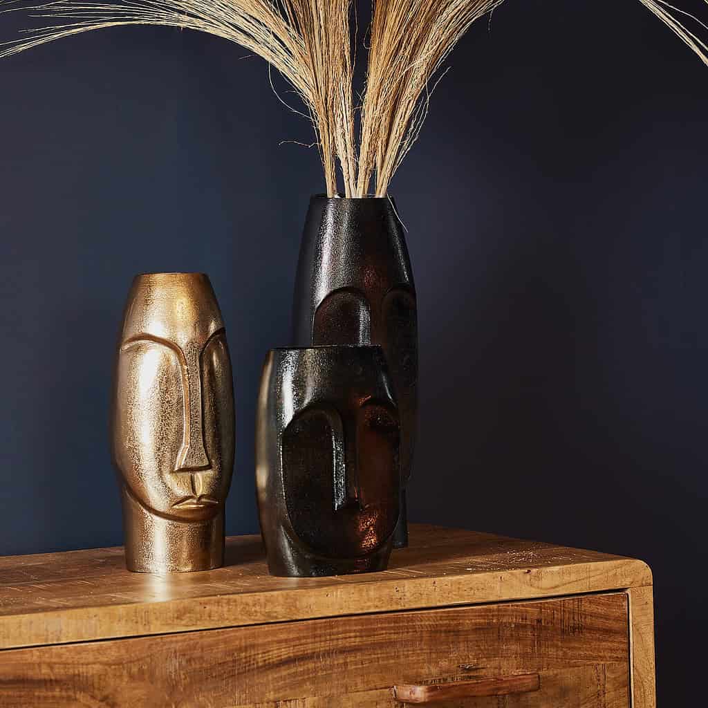 Decoratieve houten maskers en vaas met droogbloemen op houten meubel – Mokana Meubelen, uniek design, stijlvolle eyecatchers, handgemaakt, modern interieur, homedecor.