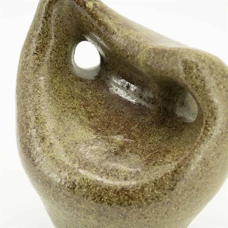 Unieke close-up van een vintage aardewerken vaas met een aardse, grove structuur en natuurlijke kleuren, perfect voor landelijke of boheemse interieurstijlen.