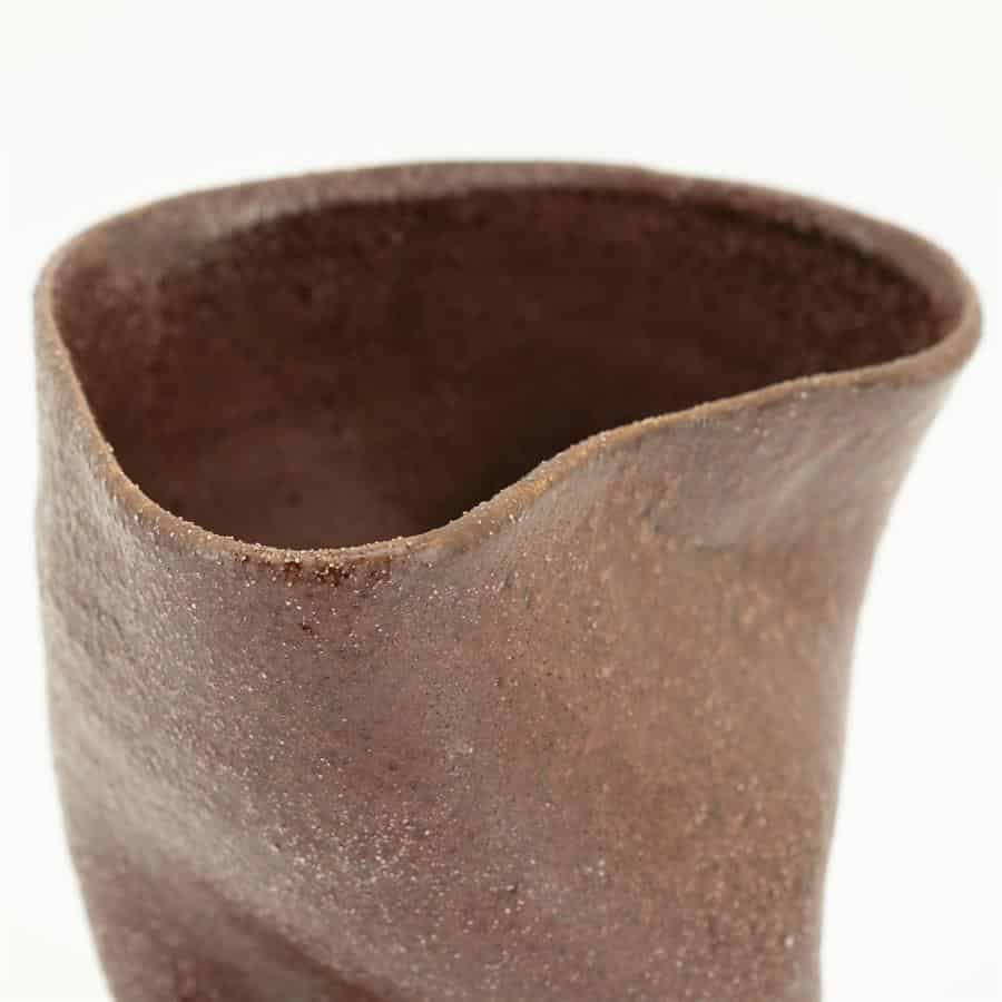 Ruwe keramieken vaas in aardetinten met unieke vorm en textuur, perfect voor modern interieur en natuurthema's.