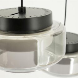 Zwarte metalen klok op luxe glazen vaas, modern design, elegante woondecoratie.