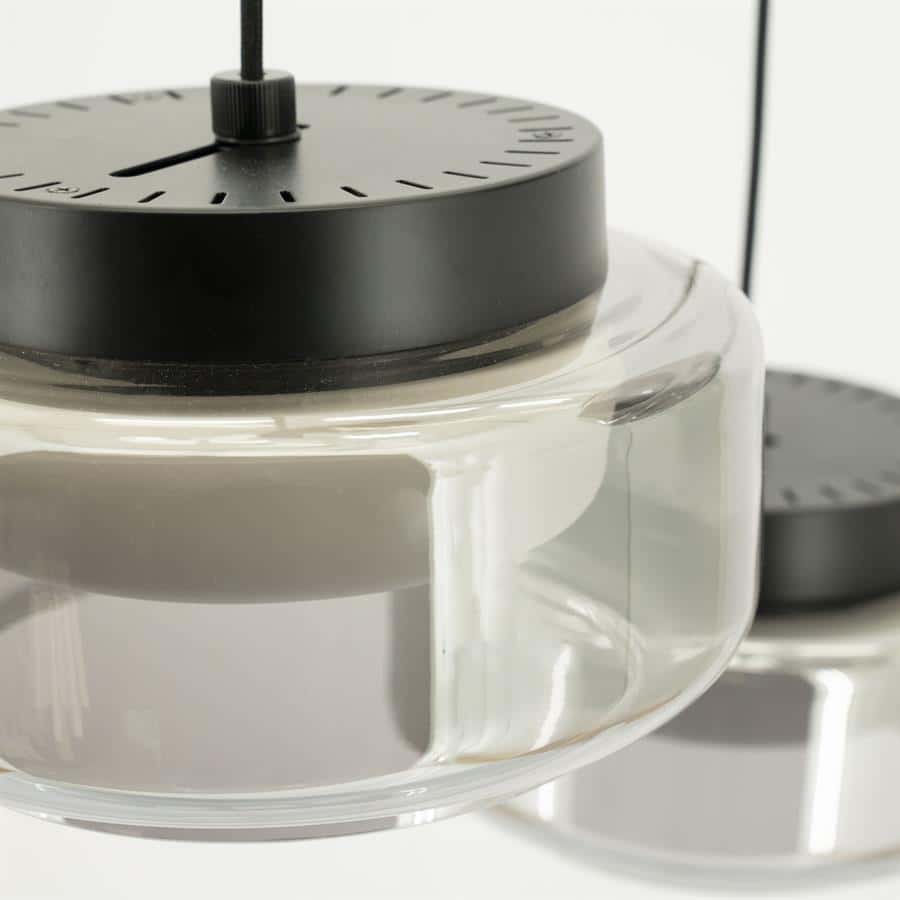 Zwarte metalen klok op luxe glazen vaas, modern design, elegante woondecoratie.