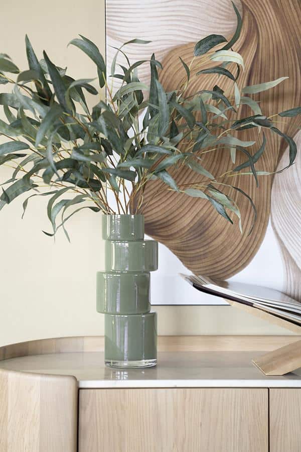 Vl uutselijke groene vazen met eucalyptus takken op een houten kast, moderne interieurdecoratie, Mokana Meubelen, stijlvolle woonaccessoires, natuurlijke uitstraling, elegant design.