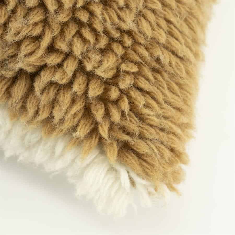 Knusse teddy stof met zachte, fluffy textuur in warm bruin en wit, perfect voor meubels en interieurdecoratie.