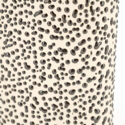 Multipel zwart en beige gestippeld roestvrijstalen meubel detail.