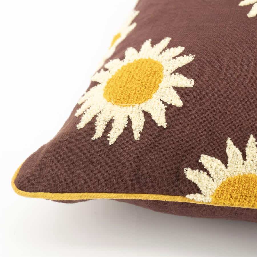 Blomstergeweven sierkussen met daisymotief op donkerrood bruin textiel, decoratief en comfortabel.