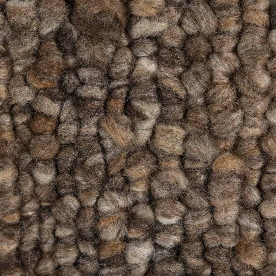 Kleurrijke wollen vloerkleed met dikke structuur en natuurlijke tinten, perfect voor een warme en gezellige inrichting.