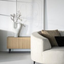 Elegante woonkamer met witte bank en design houten tv-meubel, minimalistisch interieur met witte vaas en kunstwerk, modern rustiek woondecor, duurzame meubels van Mokana Meubelen.