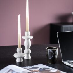 Elegant witte kandelaars op een houten tafel, gecombineerd met een zwarte mok, open magazine en een laptop, passend bij Mokana Meubelen voor een stijlvolle en moderne interieurstijl.