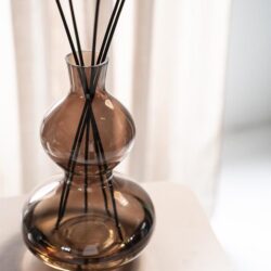 Vaas met zwart riet op een wit tafelblad, modern interieur met zachte verlichting.