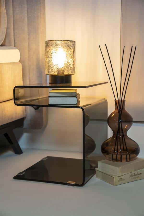 Glazen bijzettafel met zwart frame en warme lamp aan, stijlvolle woonkamer decoratie, modern interieur design, Mokana meubels, elegante kameraccessoires, unieke inrichting, houten en glazen materialen, woonstijl inspiratie.