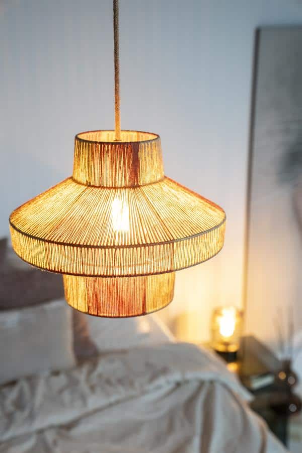 Uniek houten hanglamp boven een bed in een modern slaapkamer. Handgemaakte designverlichting van Mokana Meubelen voor een sfeervol en warm interieur.