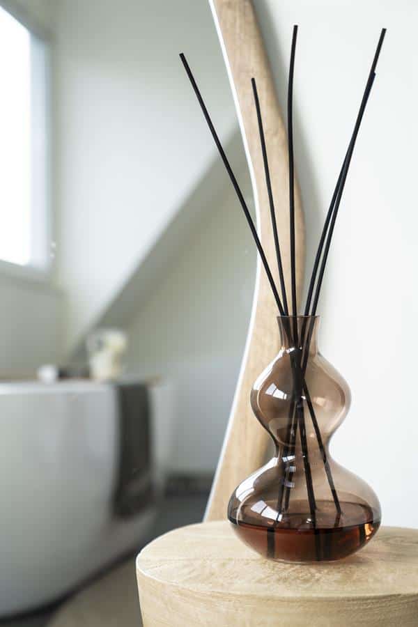 Elegant decor met zwarte diffuser sticks in een glazen vaas, perfect voor een stijlvol en rustgevend interieur, ontworpen door Mokana Meubelen.