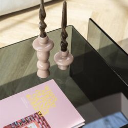 Houten kandelaars met smeedijzeren kaarsen op een glazen salontafel in een modern interieur.