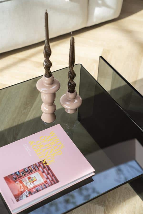 Houten kandelaars met smeedijzeren kaarsen op een glazen salontafel in een modern interieur.