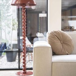 Gedraaide roze vloerlamp naast beige bank in wooninterieur, modern en stijlvol.