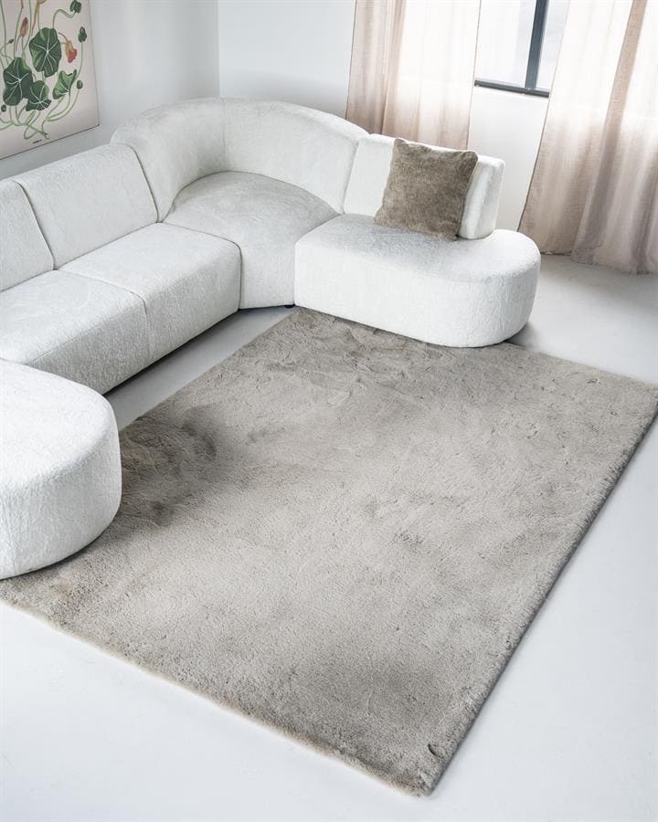 Mokana meubelen witte loungebank met zacht kussen in een moderne woonkamer met beige gordijnen en een beige vloerkleed.