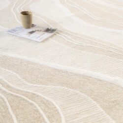Zachte beige vloerkleed met witte abstracte lijnen, luxe textuur en modern design, perfect voor een stijlvolle woonkamer of slaapkamer.
