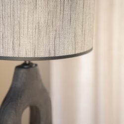 Vloerlamp met houten basis en stoffen kap, modern en stijlvol interieuraccessoire.