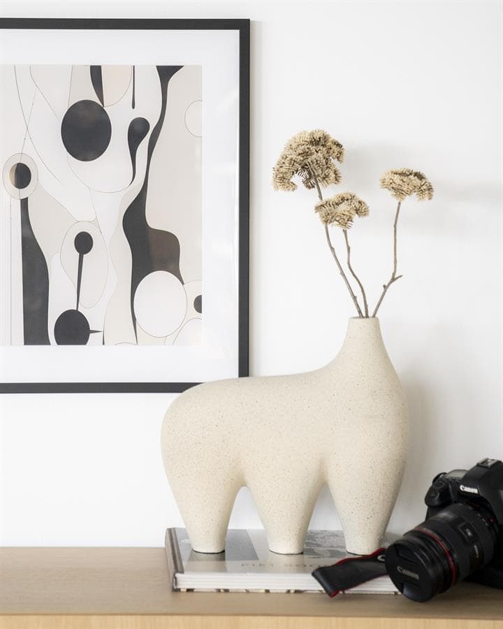 Mooi modern interieur met grappige diervaas, abstract kunstwerk en professionele camera op houten tafel, ideaal voor stijlvolle woon- en meubeldecoratie.