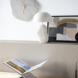 Moderne houten buffetkast met decoratieve tafelboek en muurkunst.