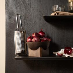 Aangepaste afbeelding met rode uien en keukengerei op een zwart houten plank, perfect voor moderne keukeninterieurs en food styling.