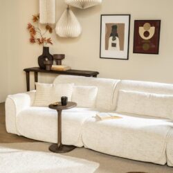 Luxe witte stoffen hoekbank in een sfeervolle woonkamer met stijlvolle zwarte salontafel, kunst aan de muur en trendy hanglampen, perfect voor een moderne en gezellige woonruimte.