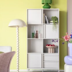 Kunststof wit boekenkast met vakken en laden in een modern interieur met groene en pastelkleuren.