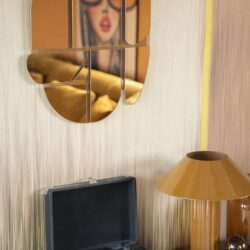 Reflectie van vrouw met grote bril op spiegel, retro interieur met platenspeler en gouden lamp, vintage woonkamer decor, stijlvolle woonaccessoires, nostalgische sfeer, modern design gecombineerd met retro elementen.