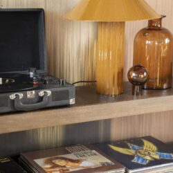 Vintage houten tafel met oranje-geel tafel lamp en vinyl platen, sfeervolle meubeldecoratie voor een warme woonkamer of woonkamer, ideaal voor muziekliefhebbers en interieur designers.
