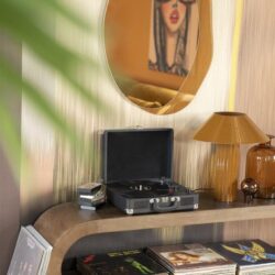 Vintage houten tv-meubel met platenspeler en vinylplaten, stijlvolle inrichting met goudkleurige lamp en spiegel, perfect voor een retro woonkamer.