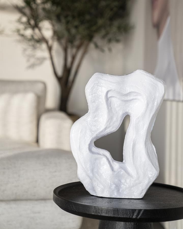 Moderne witte sculptuur van keramiek op zwart bijzettafel voor stijlvolle woondecoratie.