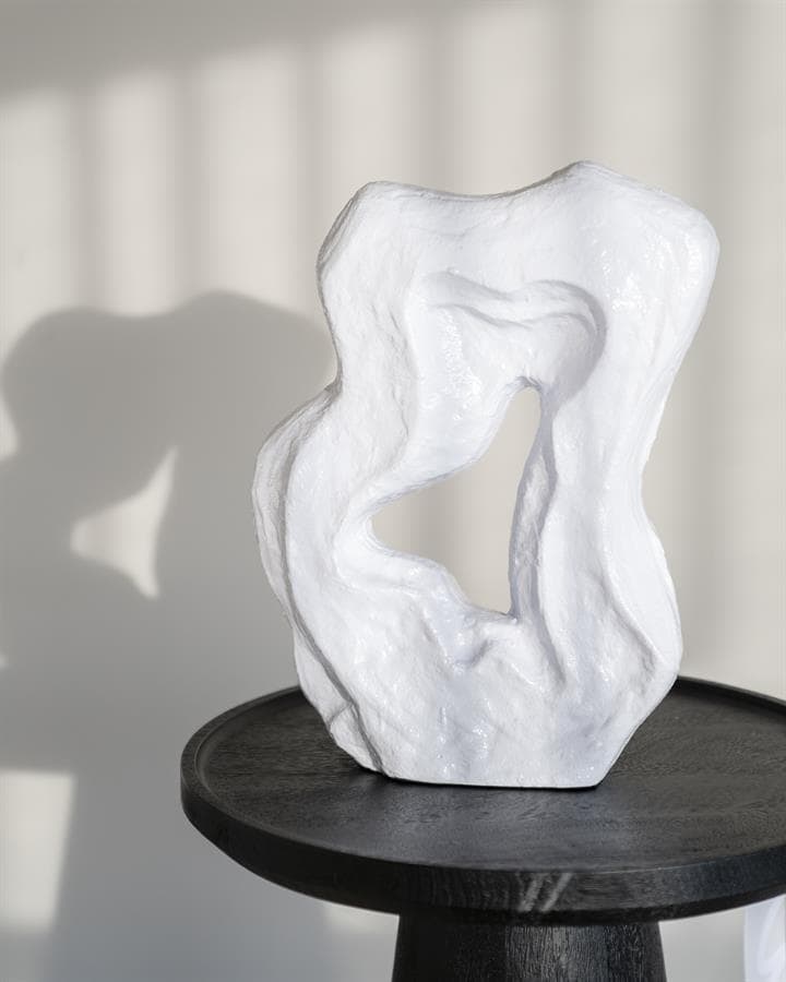 Elegante witte sculptuur van natuurlijk gevormd materiaal op zwarte houten tafel, modern decorstuk voor interieurambitie, handgemaakt kunstobject van Mokana Meubelen.