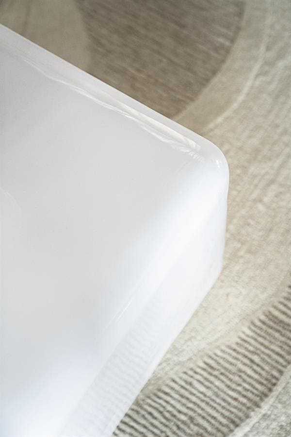 Strak wit meubel met afgeronde hoeken en glanzende afwerking in modern wooninterieur.