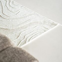 Luxueuze witte en beige tapijt met abstracte golvende patronen, perfect voor moderne woonkamerinterieurs en comfortabele sfeercreatie bij Mokana Meubelen.