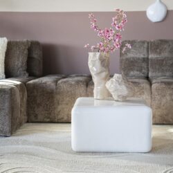 Elegante witte salontafel met keramische vazen en bloemendecor, modern interieur met bank, subtiele kleuren en gezellige sfeer.